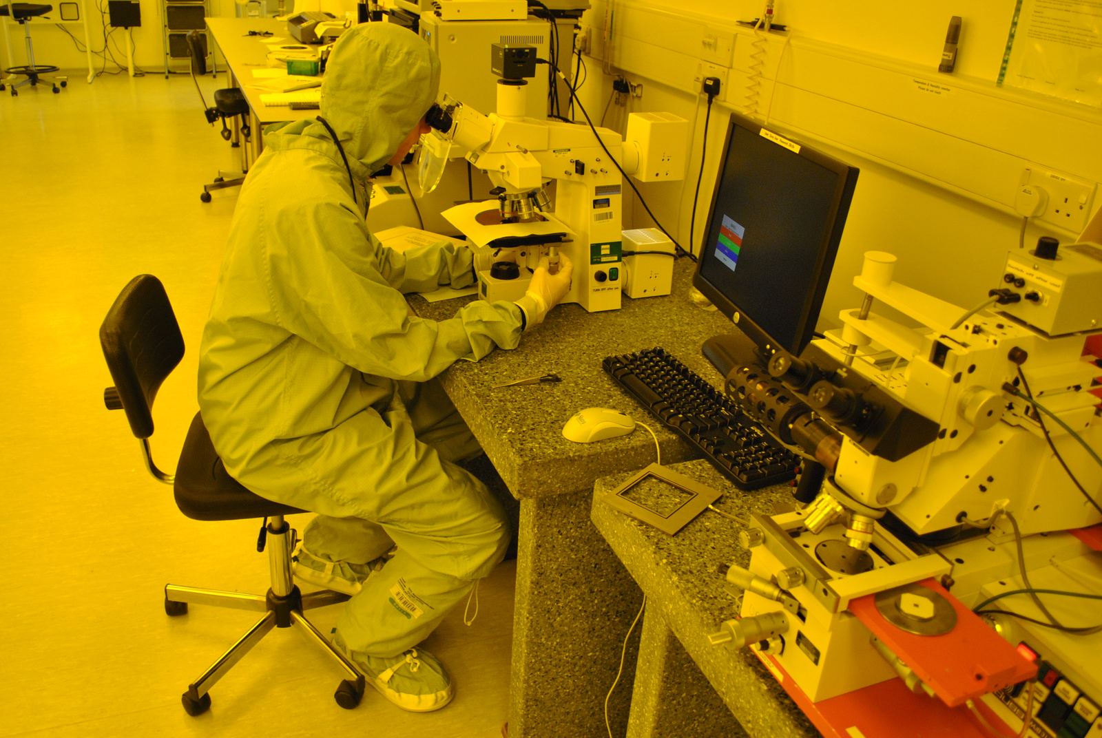 Technicians in gowned cleanroom attire working in a controlled cleanroom environment